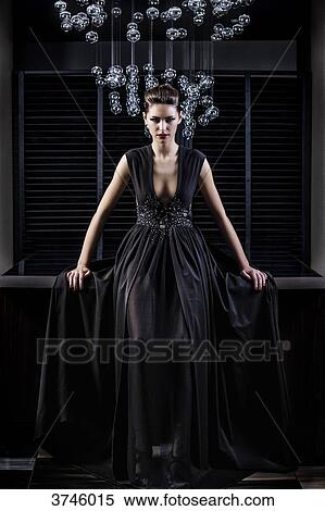 Stock Photography - Young woman in profile evening dress, sitting, looking toward the lens. Fotosearch