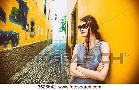 Young woman leaning against an alley, arms crossed View Large Photo Image Stock Image - Young woman leaning against an alley, arms crossed. Fotosearch