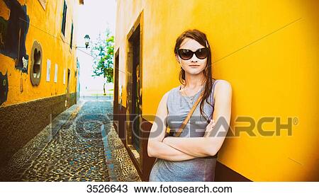 Young woman leaning against an alley, arms crossed View Large Photo Image Stock Image - Young woman leaning against an alley, arms crossed. Fotosearch