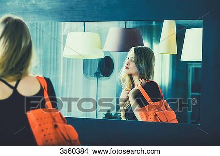 Young woman looks in the mirror before going out View Large Photo Image Picture - Young woman looks in the mirror before going out. Fotosearch