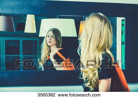 Young woman looks in the mirror before going out View Large Photo Image Stock Image - Young woman looks in the mirror before going out. Fotosearch