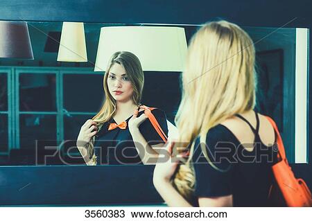 Young woman looks in the mirror before going out View Large Photo Image Stock Image - Young woman looks in the mirror before going out. Fotosearch