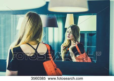 Young woman looks in the mirror before going out View Large Photo Image Stock Photography - Young woman looks in the mirror before going out. Fotosearch