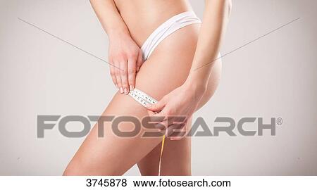 Young woman measuring her thigh View Large Photo Image Stock Photo - Young woman measuring her thigh. Fotosearch