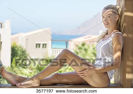 Young woman on a railing balcony View Large Photo Image Stock Photo - Young woman on a railing balcony. Fotosearch