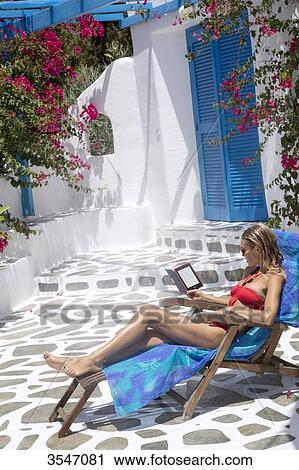 Young woman reading on a deckchair on a terrace View Large Photo Image Stock Image - Young woman reading on a deckchair on a terrace. Fotosearch