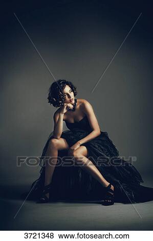 Young woman sitting in evening dress, look on the side View Large Photo Image Stock Photo - Young woman sitting in evening dress, look on the side. Fotosearch