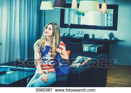 Young woman sitting on a couch in her apartment, staring at the camera View Large Photo Image Stock Photo - Young woman sitting on a couch in her apartment, staring at the camera. Fotosearch
