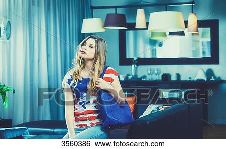 Young woman sitting on a couch in her apartment, staring at the camera View Large Photo Image Stock Photograph - Young woman sitting on a couch in her apartment, staring at the camera. Fotosearch