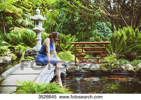 Young woman sitting on a stone bridge, feet in the water View Large Photo Image Stock Photography - Young woman sitting on a stone bridge, feet in the water. Fotosearch