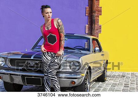 Young woman sitting on the hood of a Ford Mustang View Large Photo Image Picture - Young woman sitting on the hood of a Ford Mustang. Fotosearch