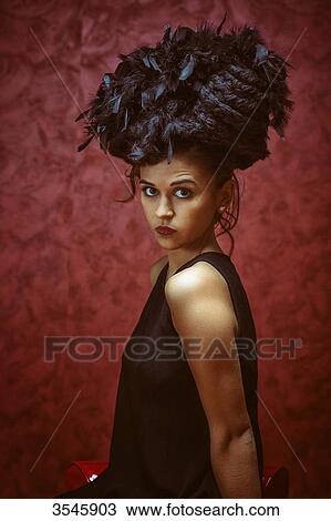 Young woman sitting with a hat made of hair and feathers View Large Photo Image Stock Image - Young woman sitting with a hat made of hair and feathers. Fotosearch