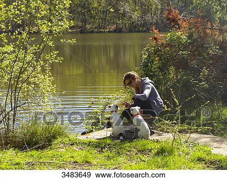 Young woman sitting with her dogs by a lake View Large Photo Image Stock Photo - Young woman sitting with her dogs by a lake. Fotosearch