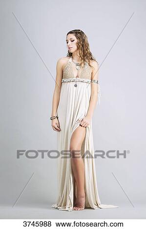 Stock Photo - Young woman standing, front, wearing a beige dress Sanhadja. Fotosearch