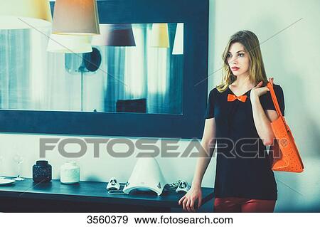 Young woman standing holding her purse View Large Photo Image Stock Photo - Young woman standing holding her purse. Fotosearch