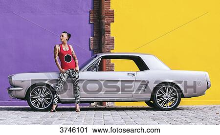 Young woman standing in front of a Ford Mustang looks to the side View Large Photo Image Stock Image - Young woman standing in front of a Ford Mustang looks to the side. Fotosearch