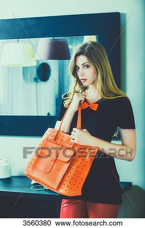 Young woman standing jealously holding her purse View Large Photo Image Stock Image - Young woman standing jealously holding her purse. Fotosearch