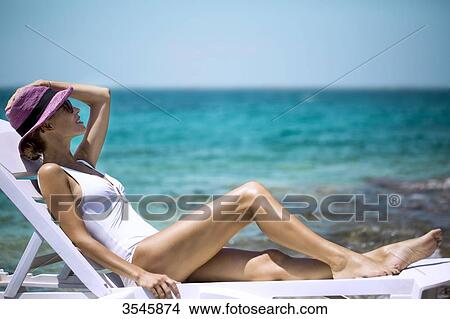 Young woman sunbathing on a deckchair View Large Photo Image Picture - Young woman sunbathing on a deckchair. Fotosearch