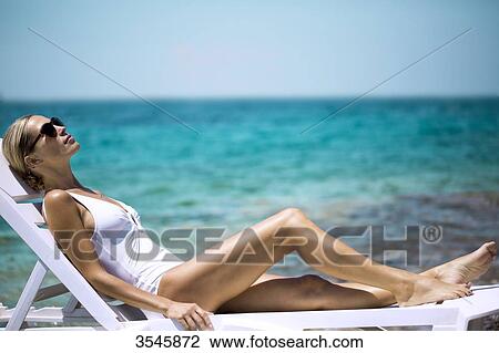 Young woman sunbathing on a deckchair View Large Photo Image Stock Image - Young woman sunbathing on a deckchair. Fotosearch