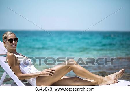 Young woman sunbathing on a deckchair View Large Photo Image Stock Image - Young woman sunbathing on a deckchair. Fotosearch