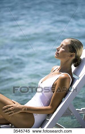 Young woman sunbathing on a deckchair View Large Photo Image Stock Photography - Young woman sunbathing on a deckchair. Fotosearch