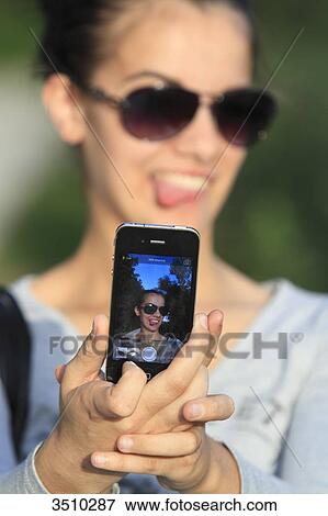 Young woman taking a selfie with her smartphone. View Large Photo Image Stock Photo - Young woman taking a selfie with her smartphone.. Fotosearch