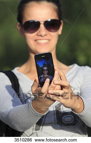 Young woman taking a selfie with her smartphone. View Large Photo Image Stock Photograph - Young woman taking a selfie with her smartphone.. Fotosearch