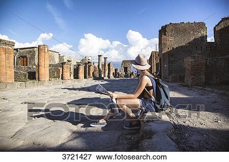 Young woman, tourist, sitting in the ruins of Pompeii, a map in hands View Large Photo Image Stock Photo - Young woman, tourist, sitting in the ruins of Pompeii, a map in hands. Fotosearch