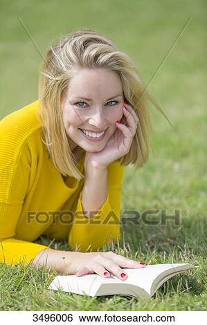 Blonde pretty woman reading a book in park smiling at camera View Large Photo Image Stock Photograph - Blonde pretty woman reading a book in park smiling at camera. Fotosearch