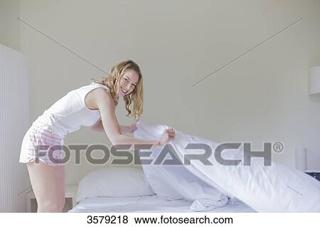 Blonde woman making bed and smiling at camera View Large Photo Image Stock Photo - Blonde woman making bed and smiling at camera. Fotosearch