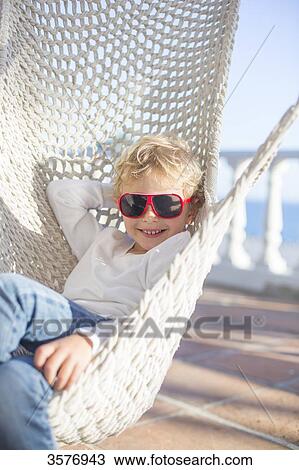Boy in hammock smiling at camera with sunglasses View Large Photo Image Stock Image - Boy in hammock smiling at camera with sunglasses. Fotosearch