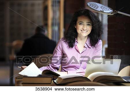 Brown-haired young woman in a library. View Large Photo Image Picture - Brown-haired young woman in a library.. Fotosearch