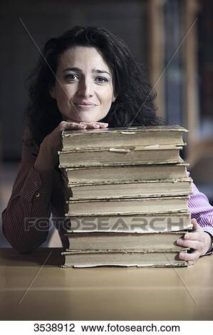 Brown-haired young woman in a library, her head and one hand resting on a pile of old books. View Large Photo Image Stock Image - Brown-haired young woman in a library, her head and one hand resting on a pile of old books.. Fotosearch