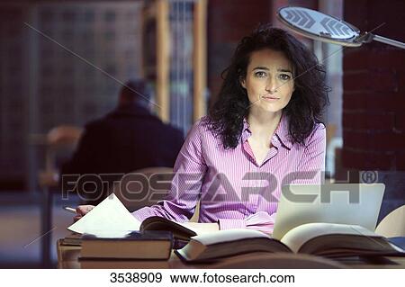 Brown-haired young woman in a library. View Large Photo Image Stock Photo - Brown-haired young woman in a library.. Fotosearch