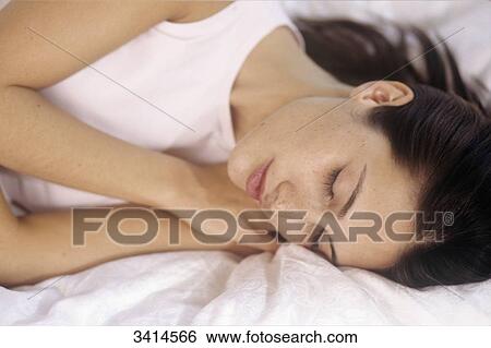 Stock Photograph - Close-up of a dark haired young woman sleeping. Fotosearch
