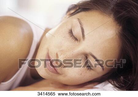 Stock Photography - Close-up of a dark haired young woman sleeping. Fotosearch