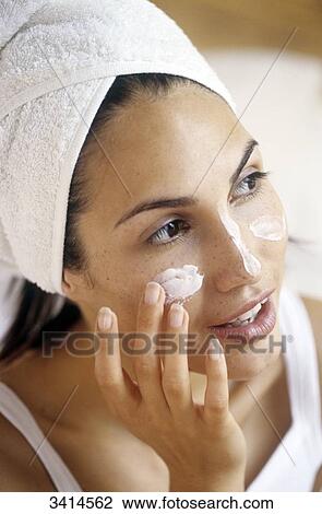 Close-up of a young woman wearing a towelling turban, applying cream to her face View Large Photo Image Stock Image - Close-up of a young woman wearing a towelling turban, applying cream to her face. Fotosearch