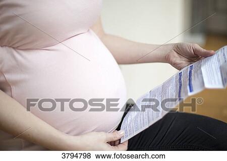 Close up of belly of a pregnant woman looking at a notice of a drug. View Large Photo Image Stock Photo - Close up of belly of a pregnant woman looking at a notice of a drug.. Fotosearch