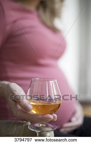 Closeup of a pregnant woman 6-month holding a glass of alcohol. View Large Photo Image Stock Photo - Closeup of a pregnant woman 6-month holding a glass of alcohol.. Fotosearch
