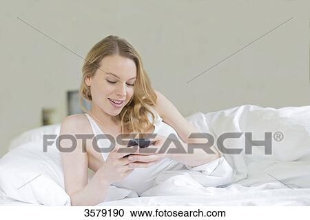 Content pretty blonde woman with mobile in bed View Large Photo Image Stock Image - Content pretty blonde woman with mobile in bed. Fotosearch