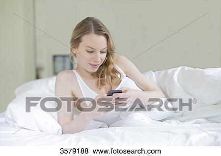 Content pretty blonde woman with mobile in bed View Large Photo Image Stock Photo - Content pretty blonde woman with mobile in bed. Fotosearch