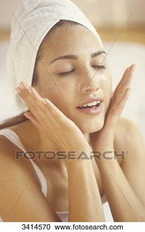 Stock Image - Dark haired young woman massaging her face. Fotosearch
