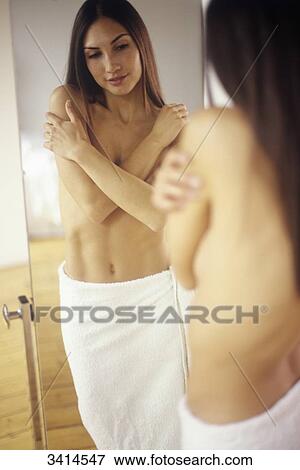 Dark haired young woman with her arms crossed, looking at herself in a long mirror View Large Photo Image Stock Photo - Dark haired young woman with her arms crossed, looking at herself in a long mirror. Fotosearch