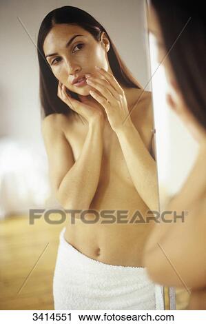 Dark haired young woman wrapped in a towel and holding her hands to her face, looking at herself in mirror View Large Photo Image Stock Image - Dark haired young woman wrapped in a towel and holding her hands to her face, looking at herself in mirror. Fotosearch