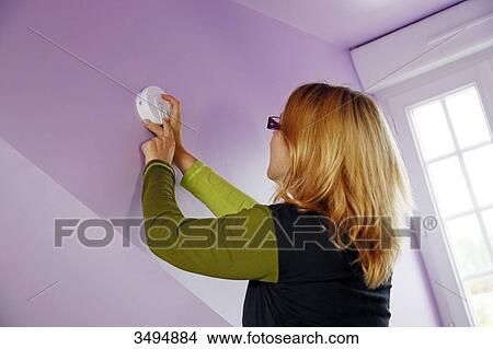 France, around Paris, 42 year old woman installing and testing a smoke detector. View Large Photo Image Picture - France, around Paris, 42 year old woman installing and testing a smoke detector.. Fotosearch