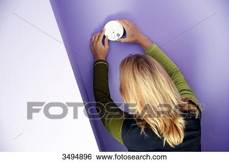France, around Paris, 42 year old woman trying to install a smoke detector next to a chimney. View Large Photo Image Stock Photograph - France, around Paris, 42 year old woman trying to install a smoke detector next to a chimney.. Fotosearch