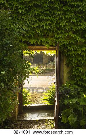 Stock Image - France, eastern France, Burgundy, garden door leading to the road, backlight. Fotosearch