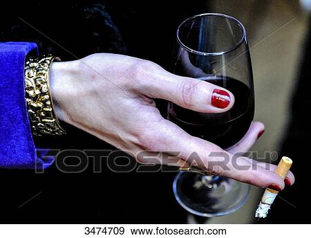 Stock Photo - France, Paris, hand of a woman holding a glass of wine and a cigaret. Fotosearch