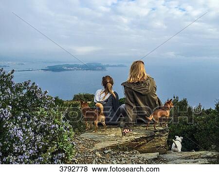 Stock Photo - France, Var, Mother and daughter view from the back looking at the mediterranean sea/. Fotosearch