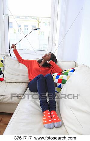 Stock Photo - France, young woman at home, doing a selfie.. Fotosearch